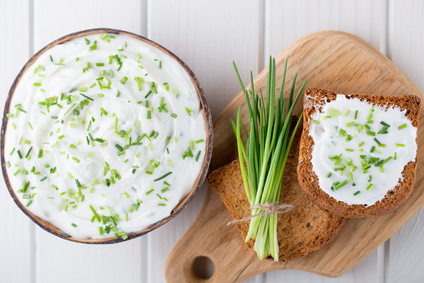 Bowl of cream cheese with green onions, dip sauce on wooden table.